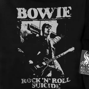 May include: Black and white graphic t-shirt featuring a silhouette of David Bowie playing guitar with the text "BOWIE" above and "ROCK 'N' ROLL SUICIDE" below the image.