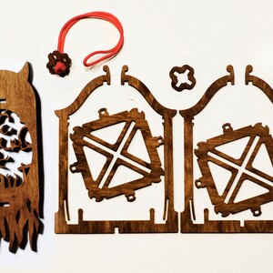 May include: A wooden craft kit for building a spooky Halloween lantern. The kit includes a pre-cut wooden base, a wooden frame, and a decorative wooden panel with a spooky tree and ghost design. The kit also includes a red string and a small wooden star.