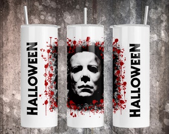 May include: Three white stainless steel tumblers with a Halloween theme. The centre tumbler features a black and white image of Michael Myers' mask with red blood splatters. The tumblers on either side have the word "HALLOWEEN" in black text with red blood splatters.