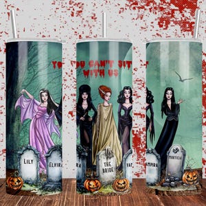 Puede incluir: Tres vasos de acero inoxidable con fondo verde e imágenes de varios personajes femeninos de películas de terror. El texto "You Can't Sit With Us" está impreso en los vasos. Los personajes incluyen Morticia, Lily, Elvira, The Bride, Vampira y Ampira.