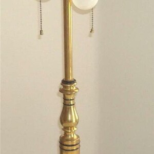 May include: A gold table lamp with two white light bulbs and a decorative base with floral designs.