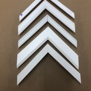 May include: A set of six white picture frames with different styles of molding. The frames are arranged in a pyramid shape, with the largest frame at the bottom and the smallest frame at the top.