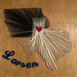 Puede incluir: Arte de hilo del estado de Texas con un corazón rojo en el centro. El texto "Larsen" está escrito en hilo azul debajo del arte.
