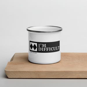 May include: White enamel camping mug with a black stripe and the text "I'm Difficult" and a black diamond ski run symbol.