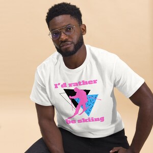 May include: White t-shirt with a pink and blue graphic of a skier and the text "I'd rather be skiing".