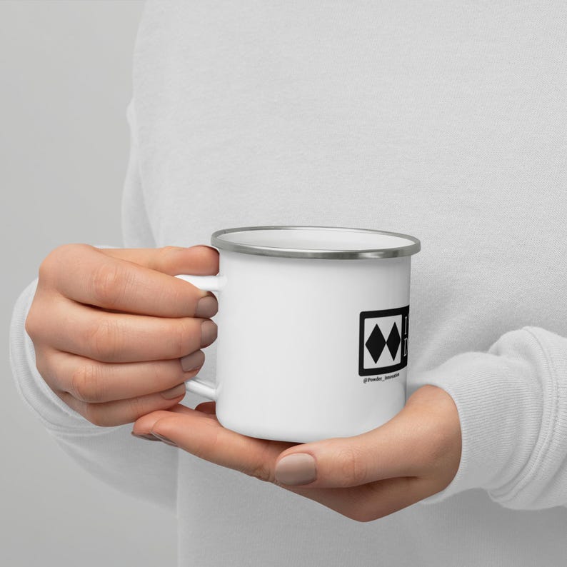 May include: White enamel mug with a black and white graphic of a ski mountain symbol. The text "#freeskier" is below the symbol.