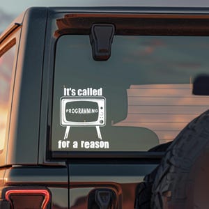 May include: A white vinyl decal applied to a vehicle window featuring a retro television set graphic with the text "It's called" above the screen, "PROGRAMMING" inside the screen, and "for a reason" positioned below the television stand.
