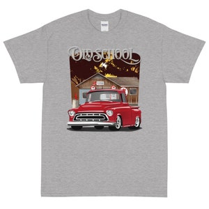 May include: A grey t-shirt with a red vintage pickup truck illustration and the text "Old School" in a stylized font. The truck is parked in front of a rustic building with a sign that reads "Mobilgas".