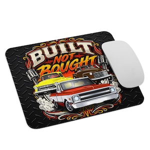 May include: A rectangular mouse pad with a black diamond plate background featuring the text BUILT NOT BOUGHT in white and orange. The design includes a yellow truck, a brown truck, and a red and white truck with stylized engine pistons.