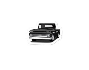 Puede incluir: Una camioneta vintage negra con parachoques y parrilla cromados. La camioneta tiene un fondo blanco.
