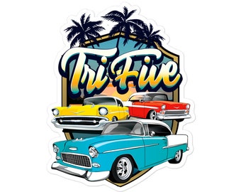 May include: A sticker depicting three classic cars in yellow, red, and blue, with a white roof on the blue car. The cars are set against a backdrop of palm trees and a sunset, with the text "Tri Five" in a retro font.