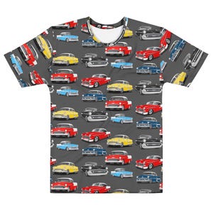 May include: A gray t-shirt featuring a repeating pattern of classic cars in various colors, including red, yellow, blue, and black. The cars are depicted in a vintage style, creating a retro aesthetic. The shirt is a crew neck.
