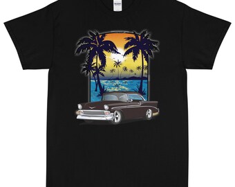 May include: Black t-shirt featuring a graphic of a classic car driving on a beach with palm trees and a sunset in the background.