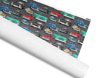 Puede incluir: Un rollo de papel estampado con un patrón repetido de camionetas clásicas en varios colores, incluyendo rojo, verde, azul, negro y amarillo, sobre un fondo gris. El papel está parcialmente enrollado, revelando un interior blanco.