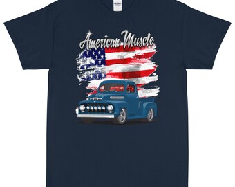 Könnte beinhalten: Marineblaues T-Shirt mit einem blauen Pickup-Truck und einem amerikanischen Flaggen-Motiv. Der Text "American Muscle" ist in Silber über dem Truck gedruckt.