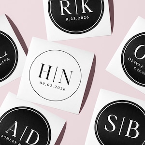 Könnte beinhalten: Weiße quadratische Aufkleber mit schwarzen kreisförmigen Designs mit Initialen, Namen und Daten. Die Aufkleber enthalten Initialen wie "NIL", "RK", "HN", "AD", "OR" und "SB" sowie Namen und Hochzeitsdaten.