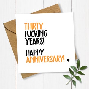 May include: A white card with black and orange text that reads "Thirty Fucking Years! Happy Anniversary!" with a small black heart.