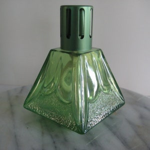 May include: A green glass pyramid-shaped oil diffuser with a metal top and a decorative design. The diffuser has a textured surface.