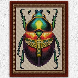 May include: Cross stitch pattern of a colorful scarab beetle with a gold hieroglyphic design on its back. The pattern is framed in a brown frame with gold accents.
