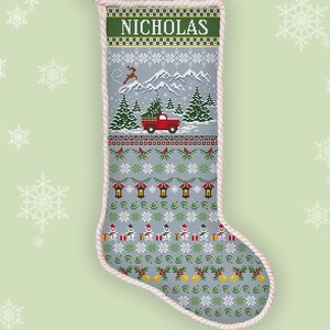 May include: A counted cross stitch Christmas stocking with the name "NICHOLAS" at the top. The design features a red truck carrying a Christmas tree, snow-covered mountains, and snowmen. The stocking is approximately 18 inches long.