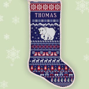May include: A counted cross stitch Christmas stocking pattern featuring the name THOMAS in white text. The design includes a white polar bear, red and white snowflakes, reindeer, and Santa Claus figures on a dark blue background with white trim.