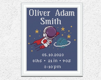 Puede incluir: Un patrón de punto de cruz azul y blanco con un astronauta de dibujos animados en el espacio con estrellas y un planeta. El patrón incluye el nombre Oliver Adam Smith, la fecha 05.10.2023 y las estadísticas de nacimiento 8lbs, 21 in, 9oz y 3:10 pm.