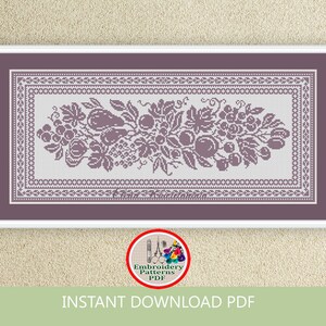 May include: A purple and white cross stitch embroidery pattern featuring a floral design with grapes, leaves, and fruit. The pattern is framed with a decorative border.