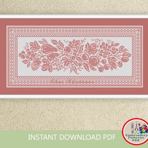 May include: A cross stitch pattern featuring a floral design with fruit and leaves. The pattern is in a white and pink color scheme and is framed in a white frame.