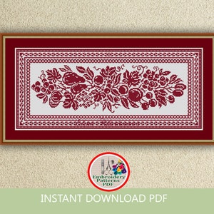 May include: A red and white cross stitch embroidery pattern featuring a floral design with grapes, leaves, and fruit. The pattern is framed in a red frame with a white mat.