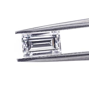 May include: A clear, rectangular, emerald-cut gemstone held in silver tweezers.