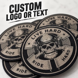 May include: Circular black and tan patches featuring a central skull wearing a helmet, surrounded by the text "LIVE HARD RIDE HARD". The design includes a star on each side and a radial pattern. The image also displays the text "CUSTOM LOGO OR TEXT".