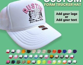 Könnte beinhalten: Eine weiße Schaumstoff-Trucker-Cap mit Netzrücken und einem Grafikdruck mit dem Text AUSTIN und Jen's Last Rodeo sowie einer Cowgirl-Illustration. Die Kappe hat einen gebogenen Schirm und einen kleinen schwarzen Aufkleber auf der Vorderseite.