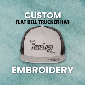 May include: A gray and black custom embroidered flat bill trucker hat with the text "Your Text/Logo Here" on the front.