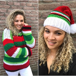 Puede incluir: Un suéter de crochet a rayas rojas, verdes, blancas y negras con mangas largas. El suéter tiene un corte holgado y está hecho con un hilo grueso. La modelo lleva pantalones blancos.