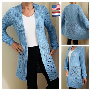 May include: A light blue crochet cardigan with a long, open front and long sleeves. The cardigan has a delicate, lacy pattern.