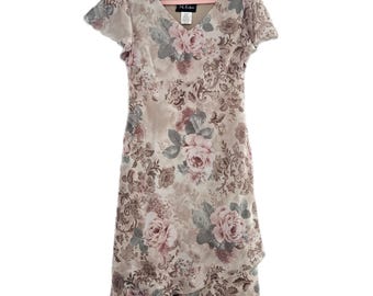May include: A beige floral print dress with a V-neck and short sleeves. The dress features a layered skirt and a pattern of pink and gray roses with green leaves. The dress is hanging on a pink hanger.