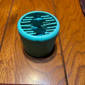 May include: A teal blue silicone hair scrunchie with a ridged design. The scrunchie is open and ready to be used.