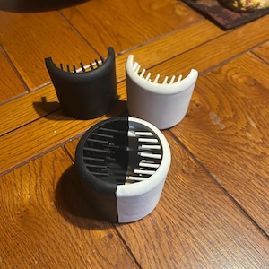 May include: Three black and white hair rollers with a comb-like design. The rollers are made of plastic and have a half black and half white design.
