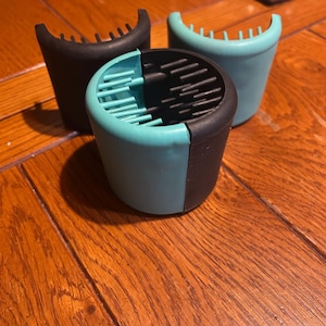 May include: Three black and turquoise blue hair rollers with a comb-like design on the top and bottom.
