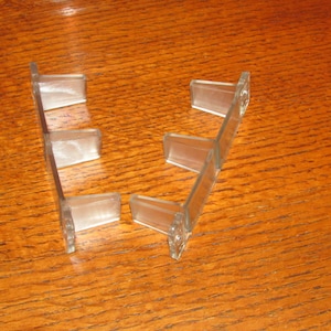 May include: Two clear plastic shelf dividers with five sections each. The dividers are designed to be used in a shelf to create separate compartments.
