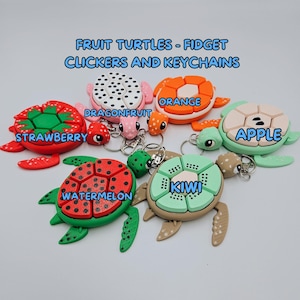 May include: Six colorful turtle-shaped keychains with different fruit designs: dragonfruit, orange, apple, strawberry, watermelon, and kiwi.  The keychains are made of plastic and have a clicker function.  The text "FRUIT TURTLES - FIDGET CLICKERS AND KEYCHAINS" is at the top of the image.