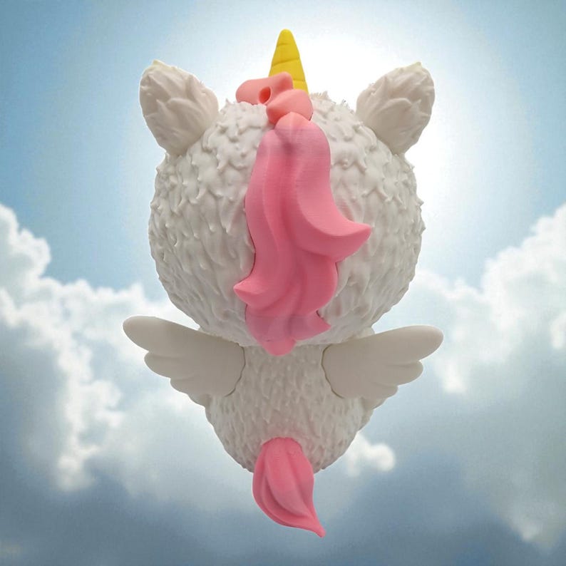 Puede incluir: Una caprichosa figura de unicornio blanco con un cuerpo texturizado, un cuerno amarillo y una melena y cola rosas. El unicornio tiene peque&ntilde;as alas blancas y est&aacute; sobre un fondo de cielo nublado.