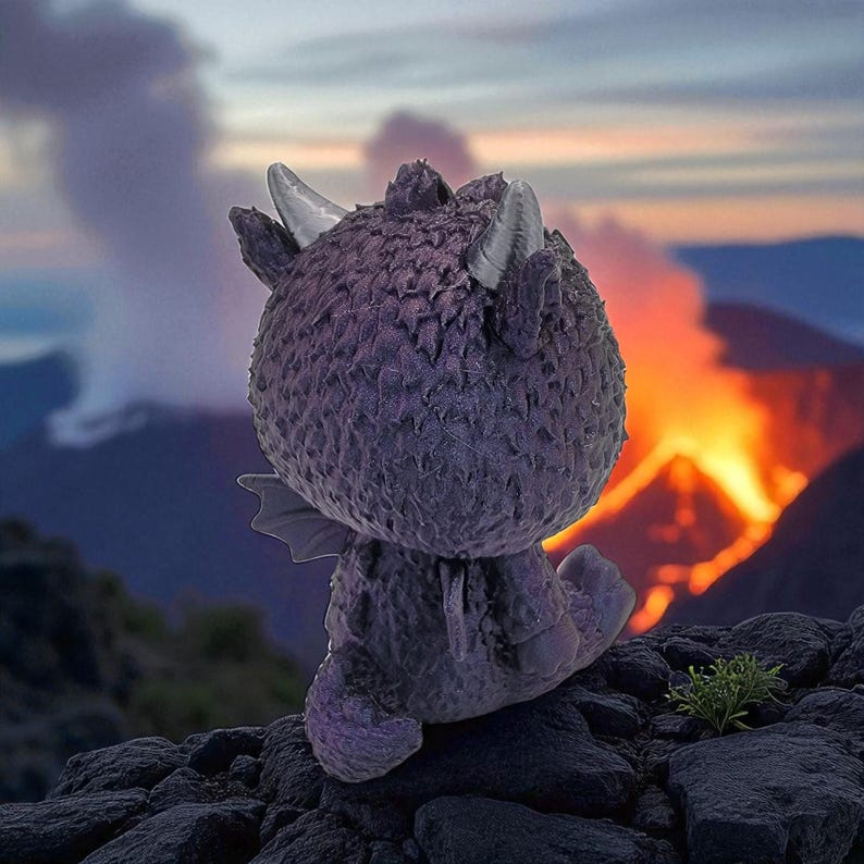 Puede incluir: Una figura de drag&oacute;n p&uacute;rpura con cuernos y alas plateadas, posada sobre una superficie rocosa. El fondo presenta una erupci&oacute;n volc&aacute;nica con llamas y humo anaranjados contra un cielo oscuro. El drag&oacute;n est&aacute; de espaldas.