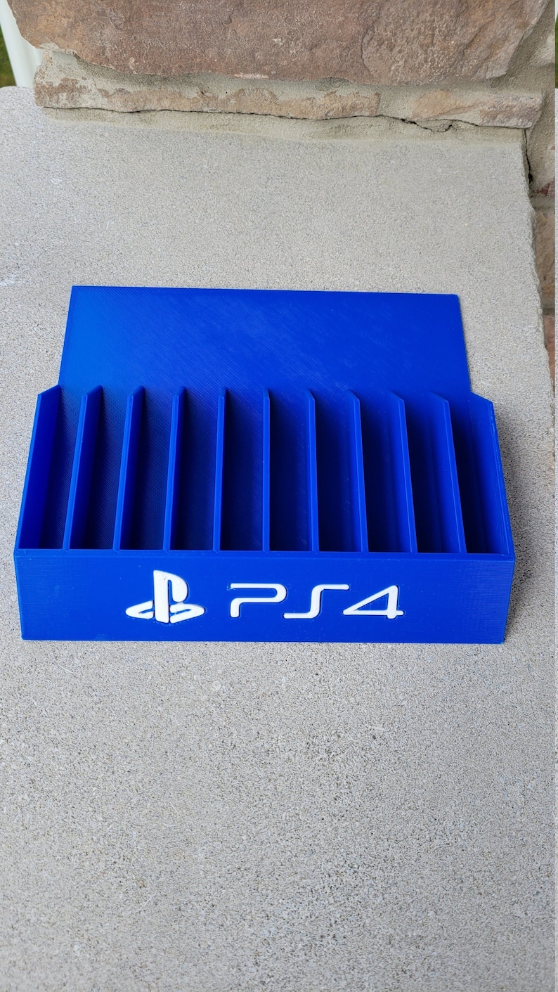 May include: A blue plastic game case with slots for storing PlayStation 4 game discs. The case has the PlayStation logo and the text "PS4" printed on the front.