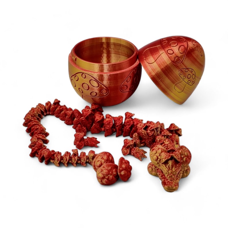 May include: A red and gold mushroom-shaped box with a lid, open to reveal a small red and gold dragon figurine. The dragon is made up of multiple pieces that can be separated and reassembled.