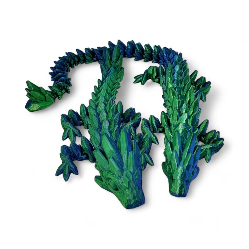 K&ouml;nnte beinhalten: Zwei gr&uuml;ne und blaue Kristall-Drachenfiguren mit detaillierten Schuppen und scharfen Z&auml;hnen. Die Drachen stehen sich gegen&uuml;ber, ihre Schw&auml;nze sind ineinander verschlungen.
