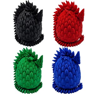 May include: Four dragon egg-shaped toys, each with a different color: black, red, green, and blue. The eggs are made of a textured material that resembles scales.