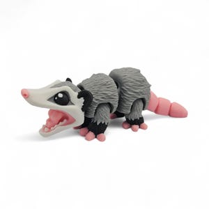 May include: A gray and white opossum figurine with a pink nose, tail, and feet. The opossum has a wide open mouth with pink gums and teeth. The figurine has black eyes and ears.