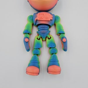 May include: A colorful, articulated astronaut toy with a rainbow gradient and a pink helmet. The toy is made of plastic and has a detailed design.