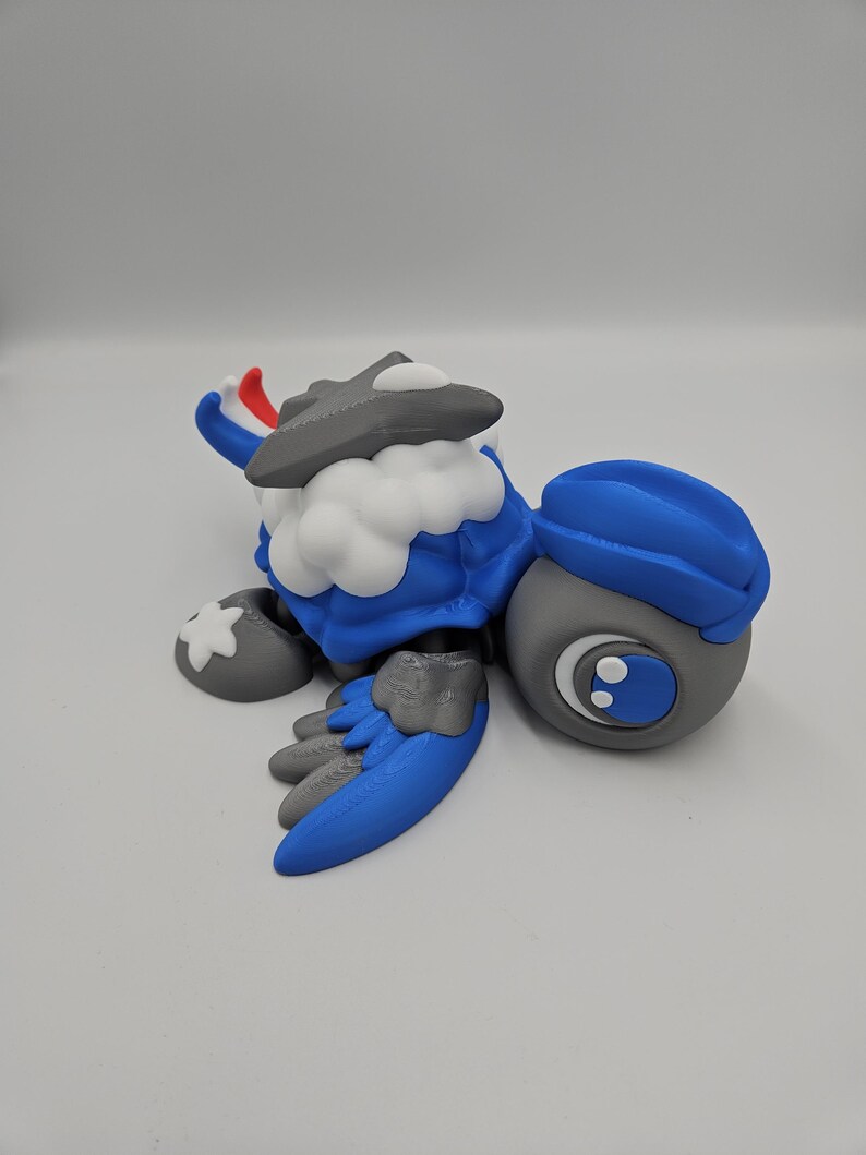 Pode incluir: Uma figura de personagem de desenho animado azul, cinza e branco. A figura tem um chap&eacute;u, asas e p&eacute;s azuis. O personagem tem um peito branco e fofo e uma cabe&ccedil;a cinza com um detalhe branco e vermelho.